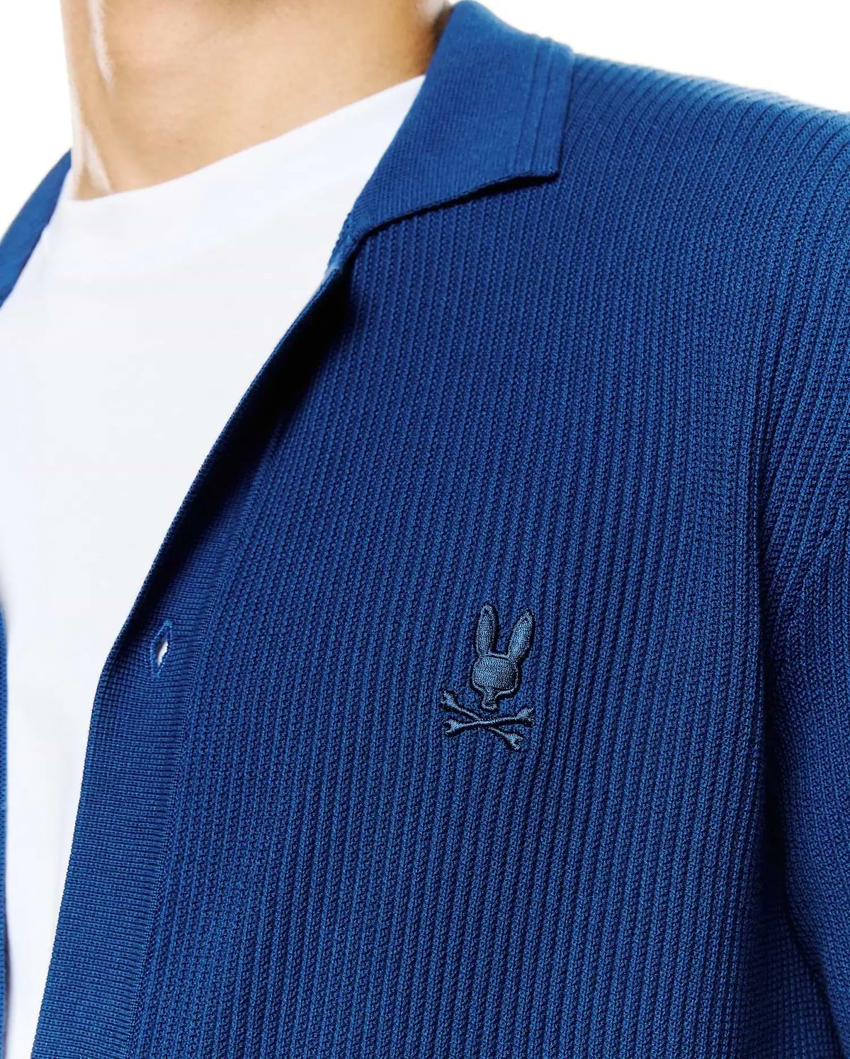 Mens Yann Knit Shirt: Deep blue ribbed knit shirt with a relaxed fit, featuring an open collar and a small, embroidered dark blue Psycho Bunny skull logo on the left chest. (2)