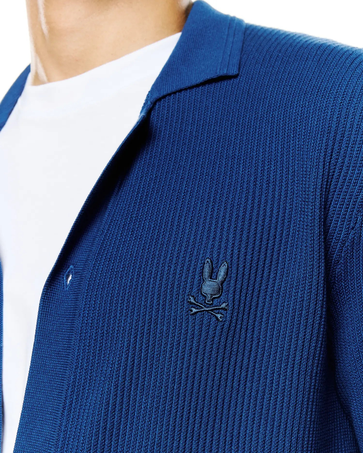 Mens Yann Knit Shirt: Deep blue ribbed knit shirt with a relaxed fit, featuring an open collar and a small, embroidered dark blue Psycho Bunny skull logo on the left chest. (2)