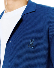 Mens Yann Knit Shirt: Deep blue ribbed knit shirt with a relaxed fit, featuring an open collar and a small, embroidered dark blue Psycho Bunny skull logo on the left chest. (2)