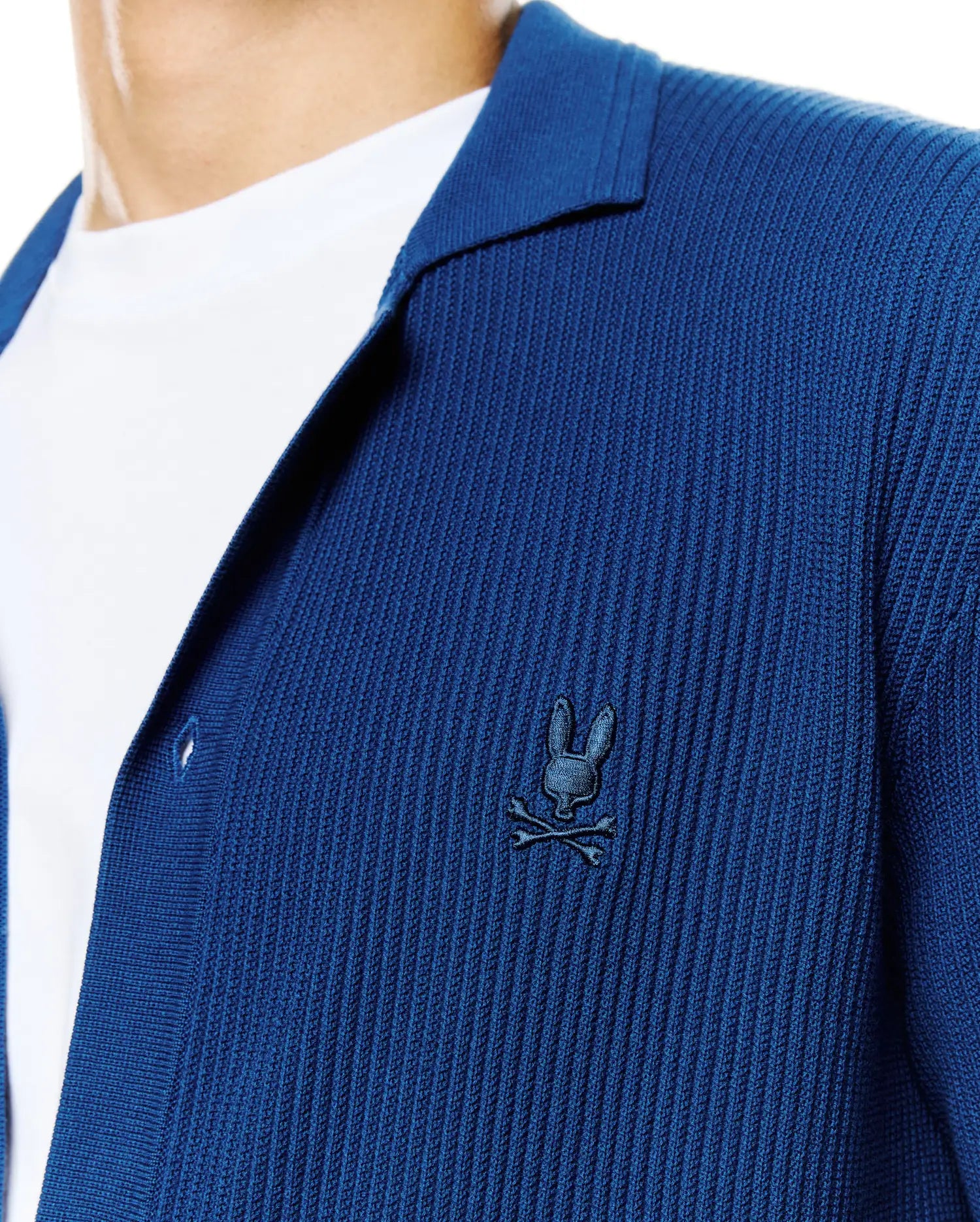 Mens Yann Knit Shirt: Deep blue ribbed knit shirt with a relaxed fit, featuring an open collar and a small, embroidered dark blue Psycho Bunny skull logo on the left chest. (2)