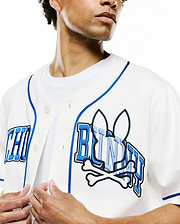 Mens Nathaniel Baseball Shirt in off-white, with royal blue piping and a large, textured blue embroidered Psycho Bunny skull and crossbones logo with PSYCHO BUNNY text across the chest, in a classic fit.