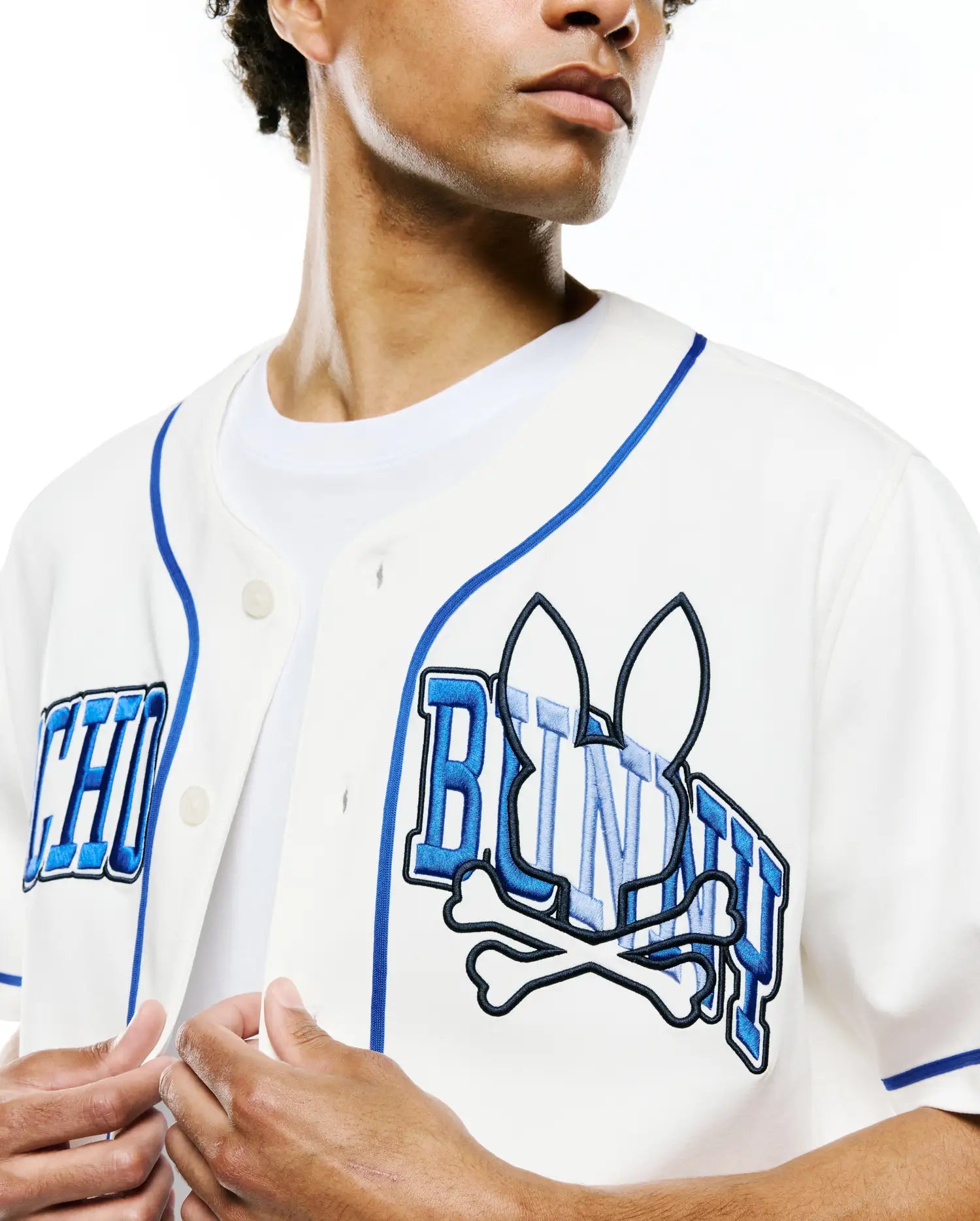 Mens Nathaniel Baseball Shirt in off-white, with royal blue piping and a large, textured blue embroidered Psycho Bunny skull and crossbones logo with PSYCHO BUNNY text across the chest, in a classic fit.