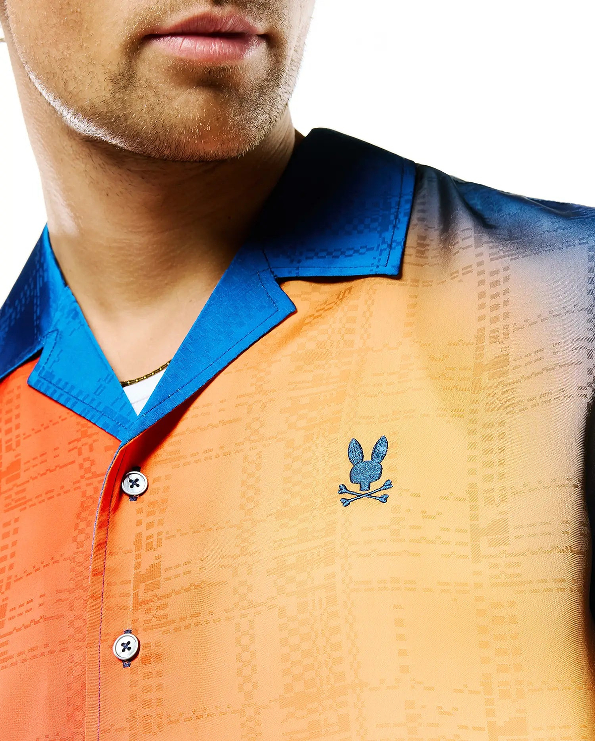 Mens Zander Jacquard Shirt: Ombre orange-yellow-dark blue camp collar shirt featuring a subtle geometric jacquard pattern, bright blue collar, and small embroidered dark blue Psycho Bunny skull logo on the left chest.