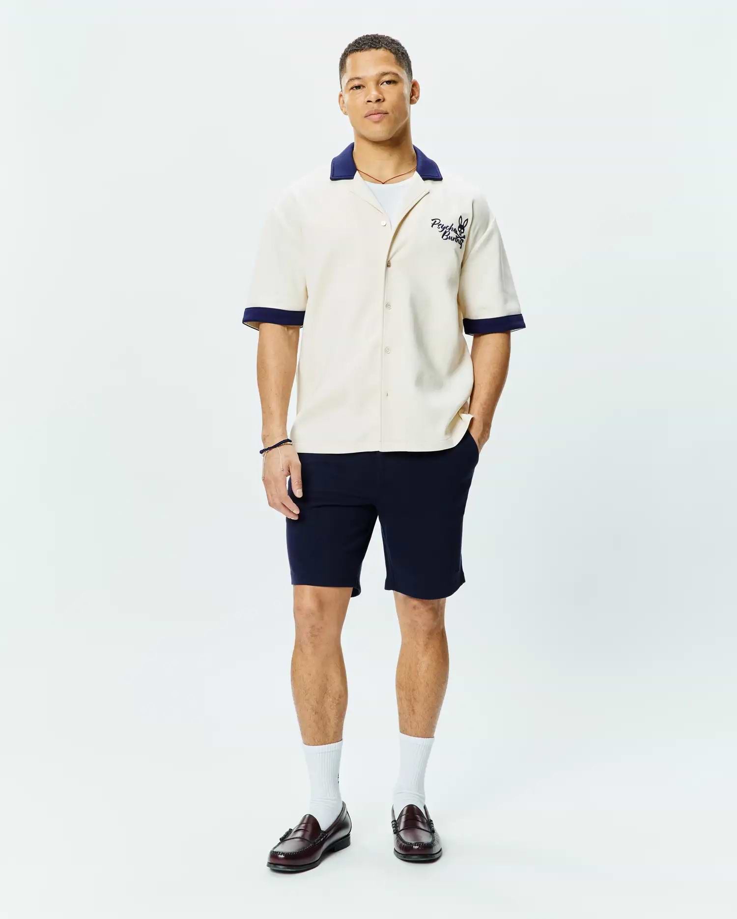 Mens Kelly Oversized Shirt in cream, a short-sleeve button-up with a relaxed fit, featuring a contrasting navy blue camp collar and cuffs, and an embroidered Psycho Bunny skull logo on the left chest.