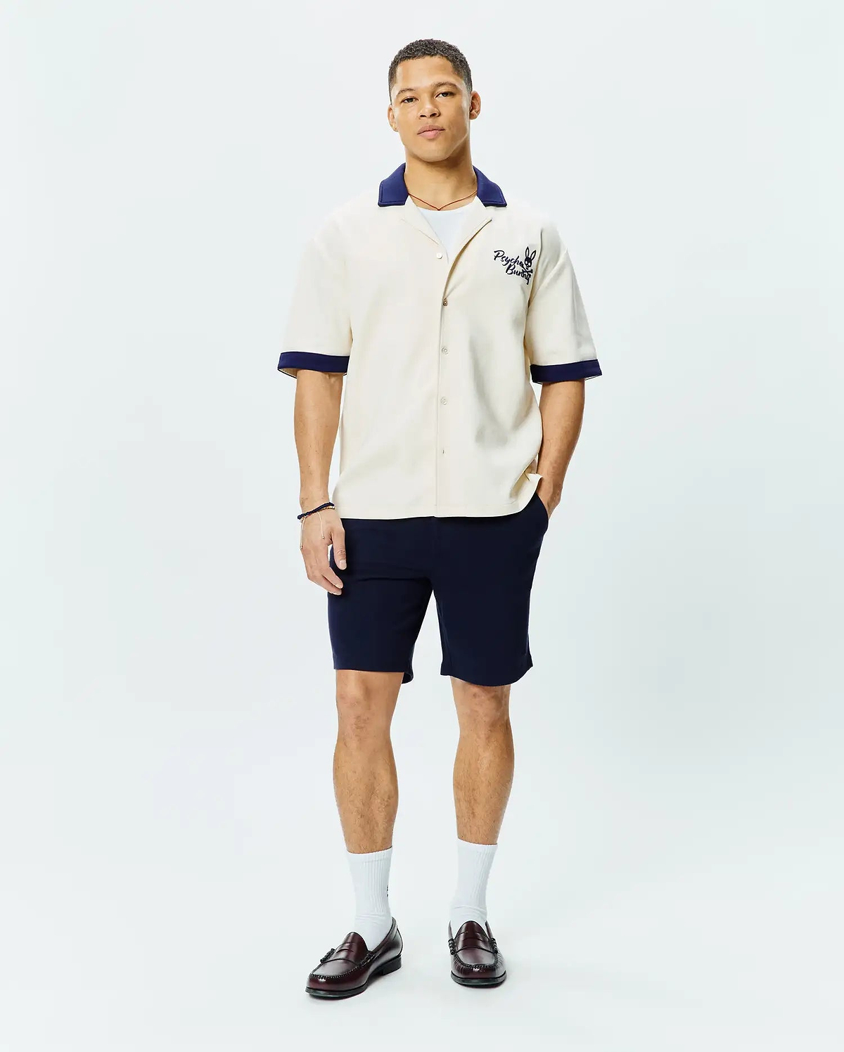 Mens Kelly Oversized Shirt in cream, a short-sleeve button-up with a relaxed fit, featuring a contrasting navy blue camp collar and cuffs, and an embroidered Psycho Bunny skull logo on the left chest.