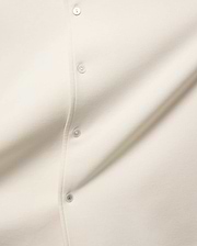 MENS KELLY OVERSIZED SHIRT in ecru, featuring a smooth jersey fabric, a button placket with cream buttons, and a distinctive green accent on the bottom button.