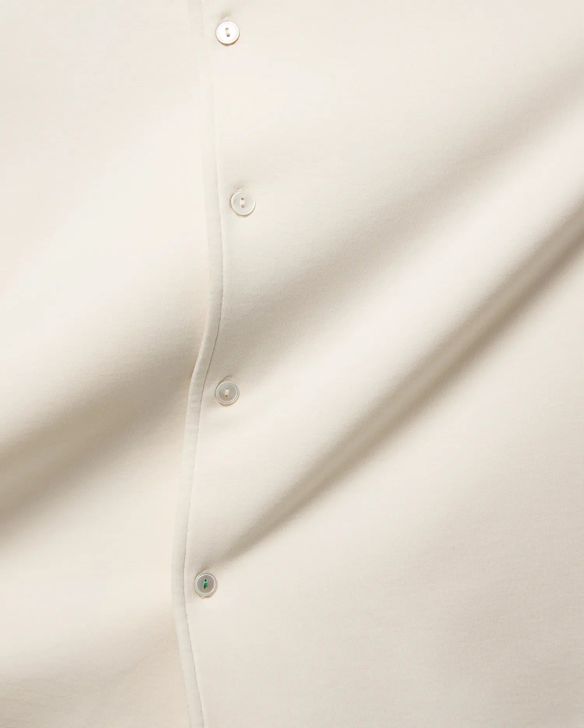 MENS KELLY OVERSIZED SHIRT in ecru, featuring a smooth jersey fabric, a button placket with cream buttons, and a distinctive green accent on the bottom button.