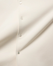 MENS KELLY OVERSIZED SHIRT in ecru, featuring a smooth jersey fabric, a button placket with cream buttons, and a distinctive green accent on the bottom button.
