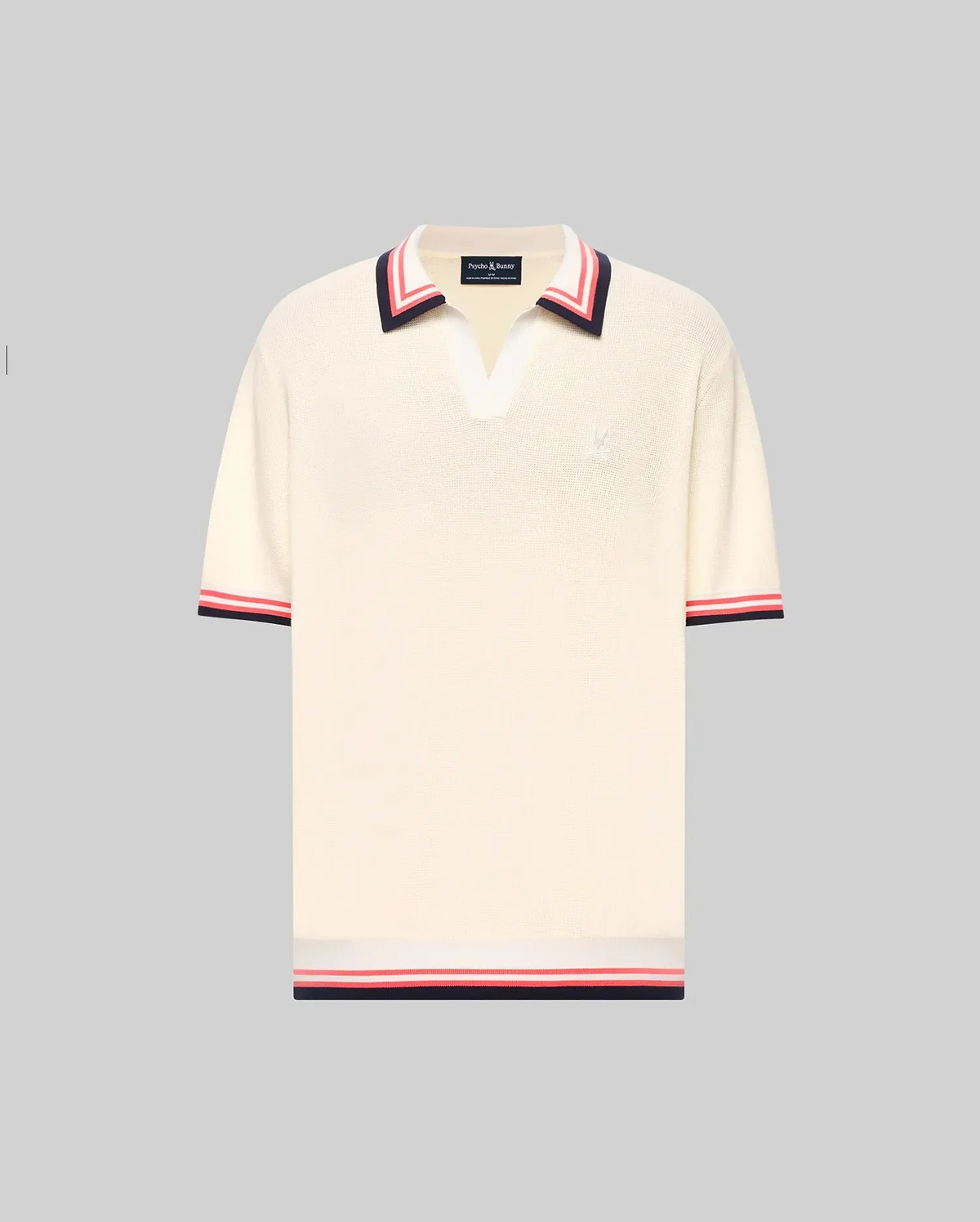 The Psycho Bunny MENS CARTER JOHNNY COLLAR KNIT POLO (MT0400093) is a cream, 100% cotton short-sleeve polo with a deep V-neck Johnny collar and red/navy colorblocked stripes on the collar, sleeves, and hem, shown on a light gray background. (5)