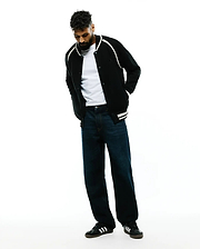 Black knit Mens Rafferty Cardigan, a classic fit varsity style featuring white shoulder piping, ribbed cuffs with double white stripes, and a small embroidered Psycho Bunny skull logo on the left chest. (4)