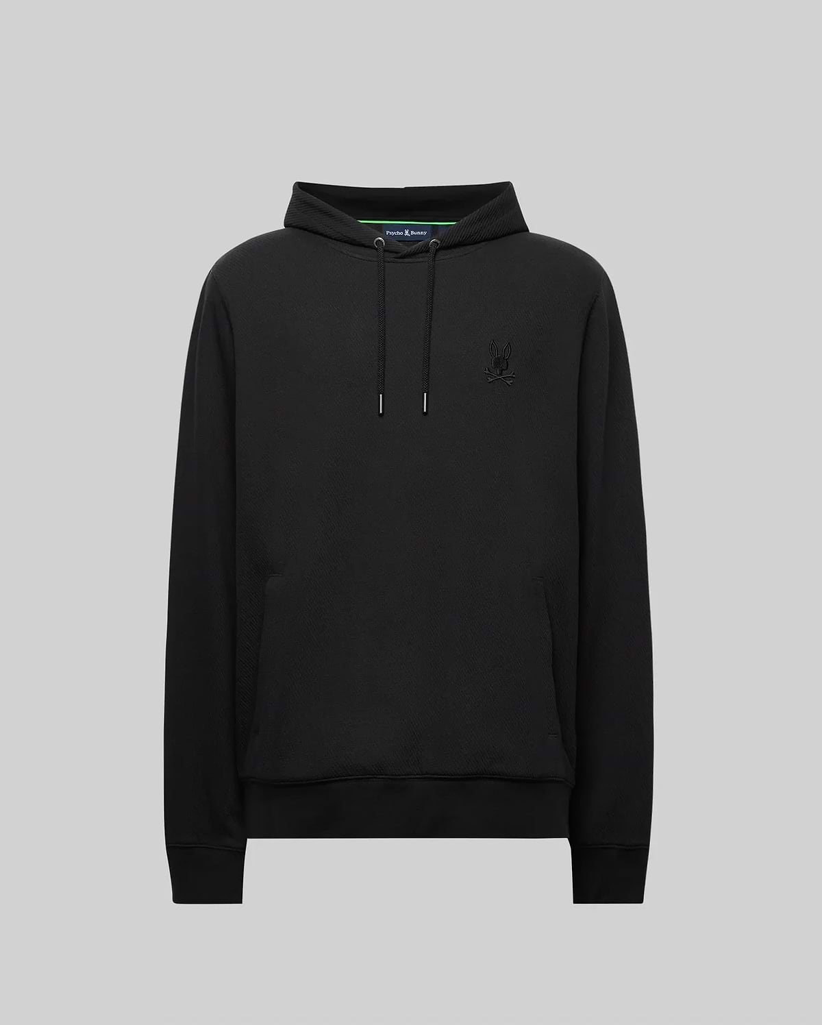 The Psycho Bunny MENS KAI HOODIE (MT0500019) in black features drawstrings, a front pocket, and a subtle embroidered Bunny logo on the left chest, shown against a plain gray background.
