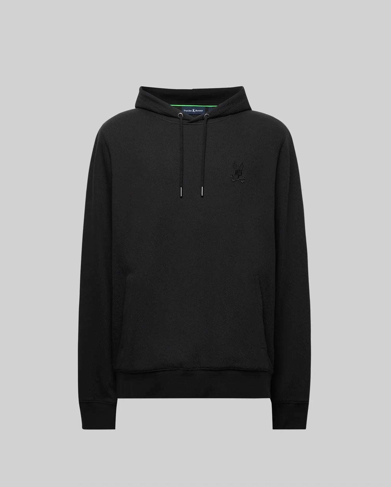 The Psycho Bunny MENS KAI HOODIE (MT0500019) in black features drawstrings, a front pocket, and a subtle embroidered Bunny logo on the left chest, shown against a plain gray background.