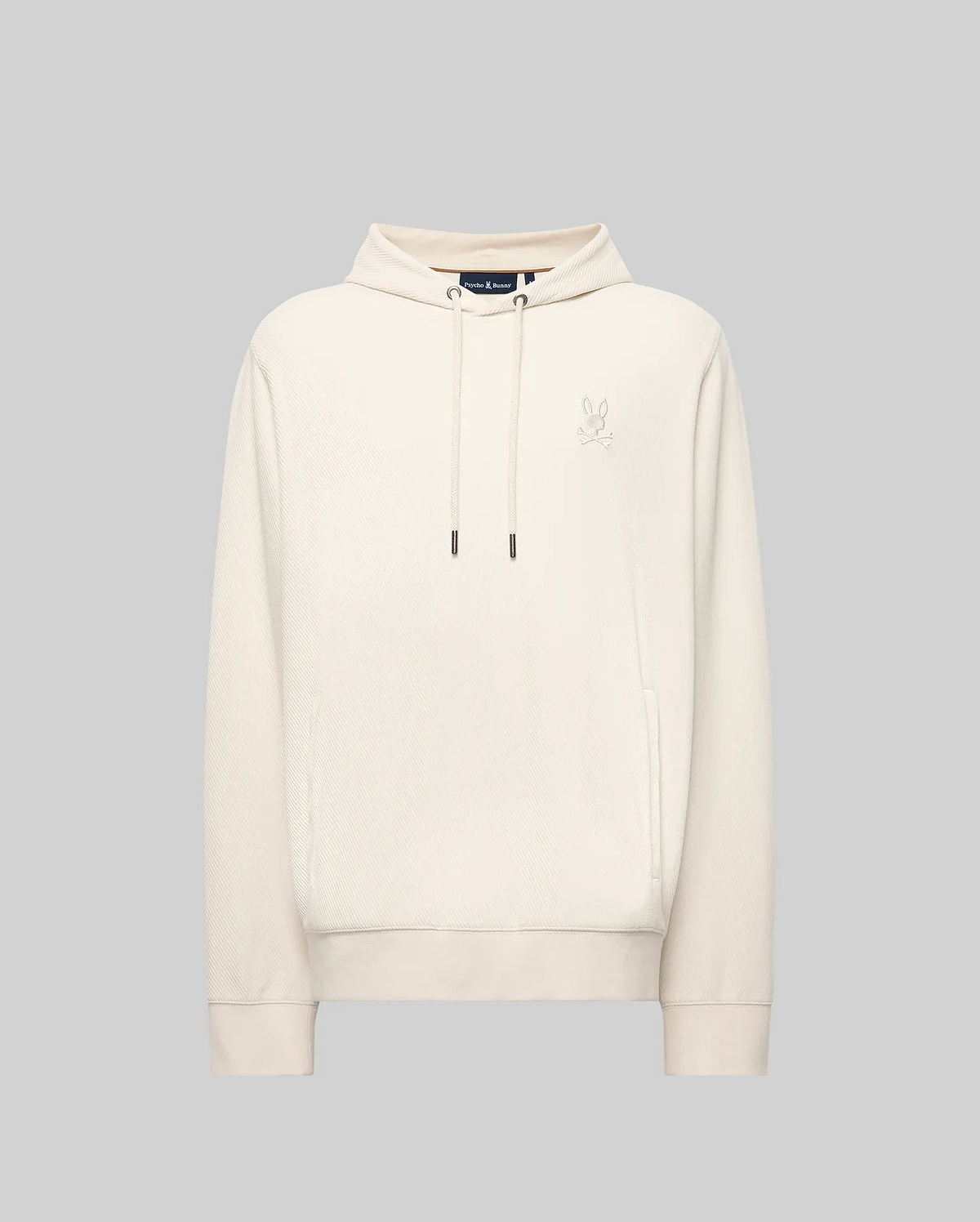 The MENS KAI TWILL TEXTURE HOODIE - MT0500019 by Psycho Bunny features a cream color, drawstrings, a small embroidered Bunny logo on the left chest, and ribbed cuffs and hem, shown against a light gray background.