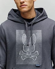 A person wears the Psycho Bunny MENS GRANT HOODIE (MT0500032), featuring a premium cotton build with an embroidered bunny head above crossed bones, inspired by the skull and crossbones, set against a backdrop of digital-style horizontal lines.