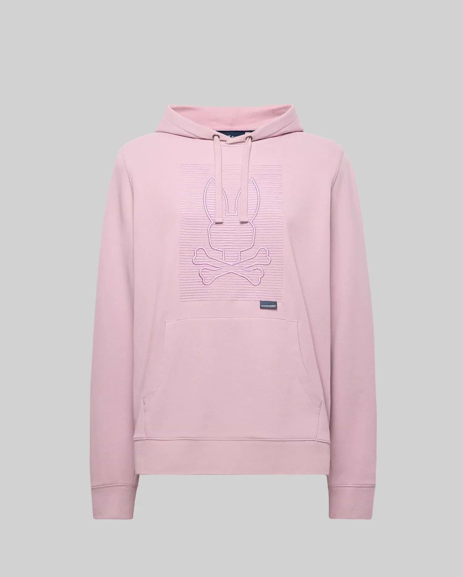 The Psycho Bunny MENS GRANT HOODIE - MT0500032 is a light pink premium cotton-blend hoodie with long sleeves, a front pocket, and a raised zig-zag embroidered bunny head above crossed bones on the chest. Plain gray background.