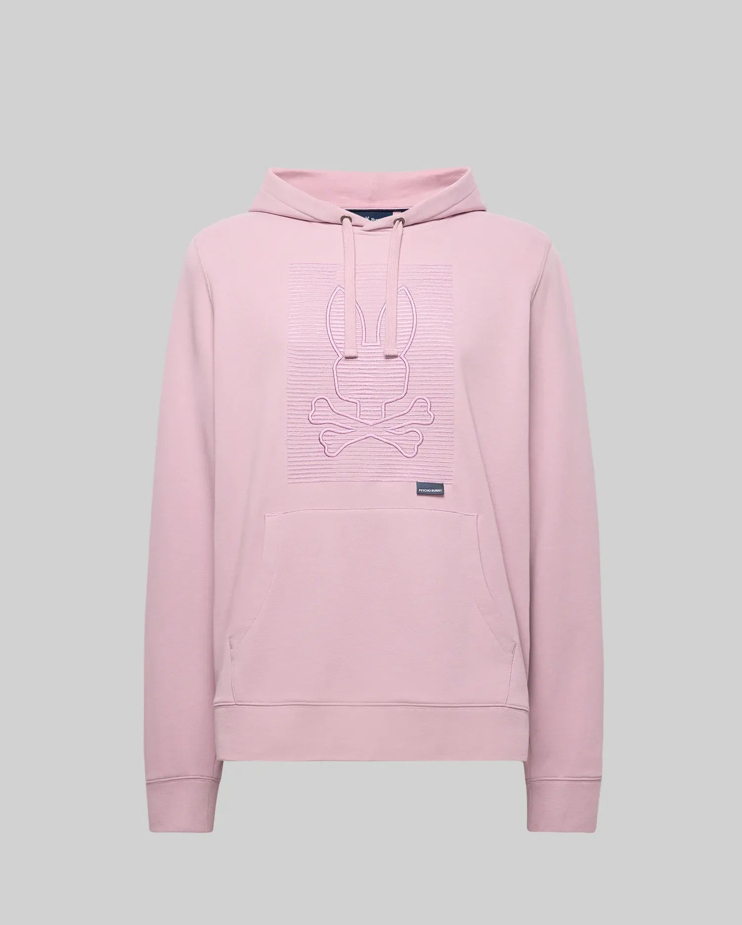 The Psycho Bunny MENS GRANT HOODIE - MT0500032 is a light pink premium cotton-blend hoodie with long sleeves, a front pocket, and a raised zig-zag embroidered bunny head above crossed bones on the chest. Plain gray background.