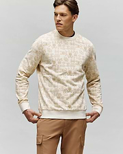 A man wears the Psycho Bunny MENS REED FLOCK CREW - MT0500041 with bunny print and tan cargo pants, standing with hands by his sides and looking left against a plain background.