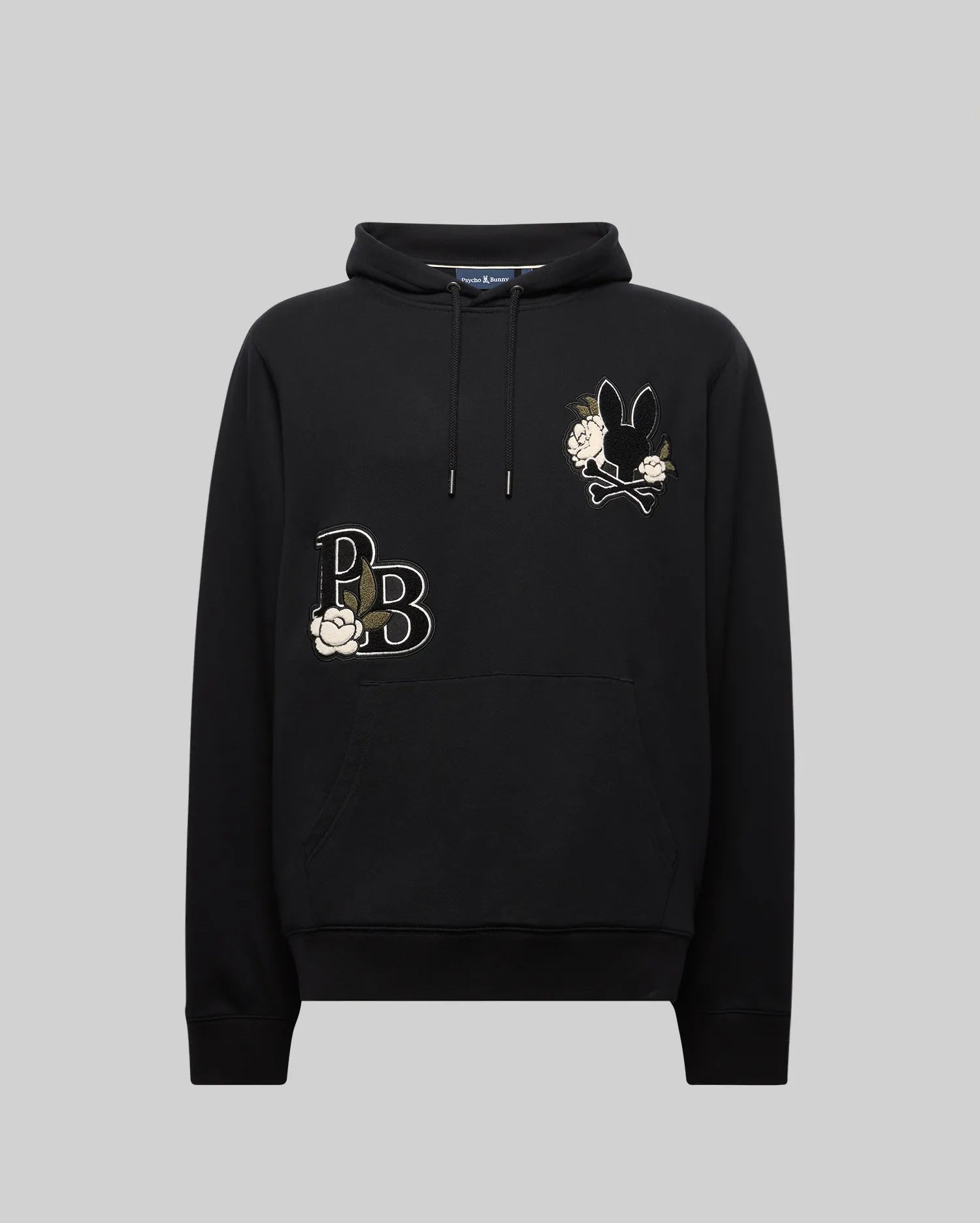 The Psycho Bunny MENS AUGUSTE HOODIE (MT0500043) is a black regular fit hoodie with a drawstring hood, chenille floral details, stylized "PB" letters, and a floral bunny design on the upper left chest, shown on a plain gray background.