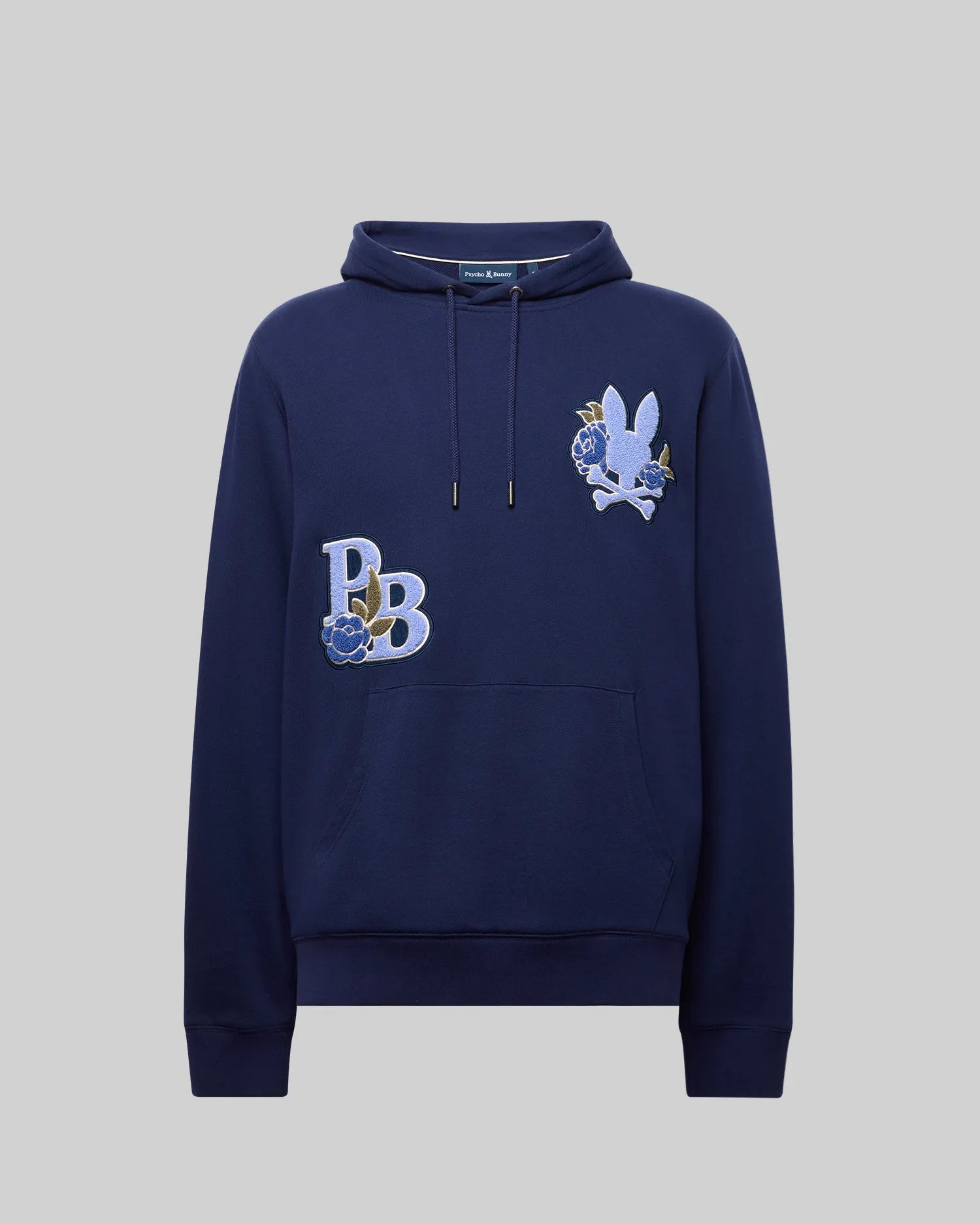 The Psycho Bunny MENS AUGUSTE HOODIE (MT0500043) is a navy blue, regular fit premium cotton hoodie with chenille floral patches: "PB" with a blue rose, and a white bunny with a blue rose. Features front pocket and drawstring hood.