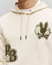 The Psycho Bunny MENS AUGUSTE HOODIE - MT0500043 is a cream regular-fit premium cotton hoodie featuring embroidered bunny head with crossed bones and flowers on the right chest, and "PB" with chenille floral detail on the left side.