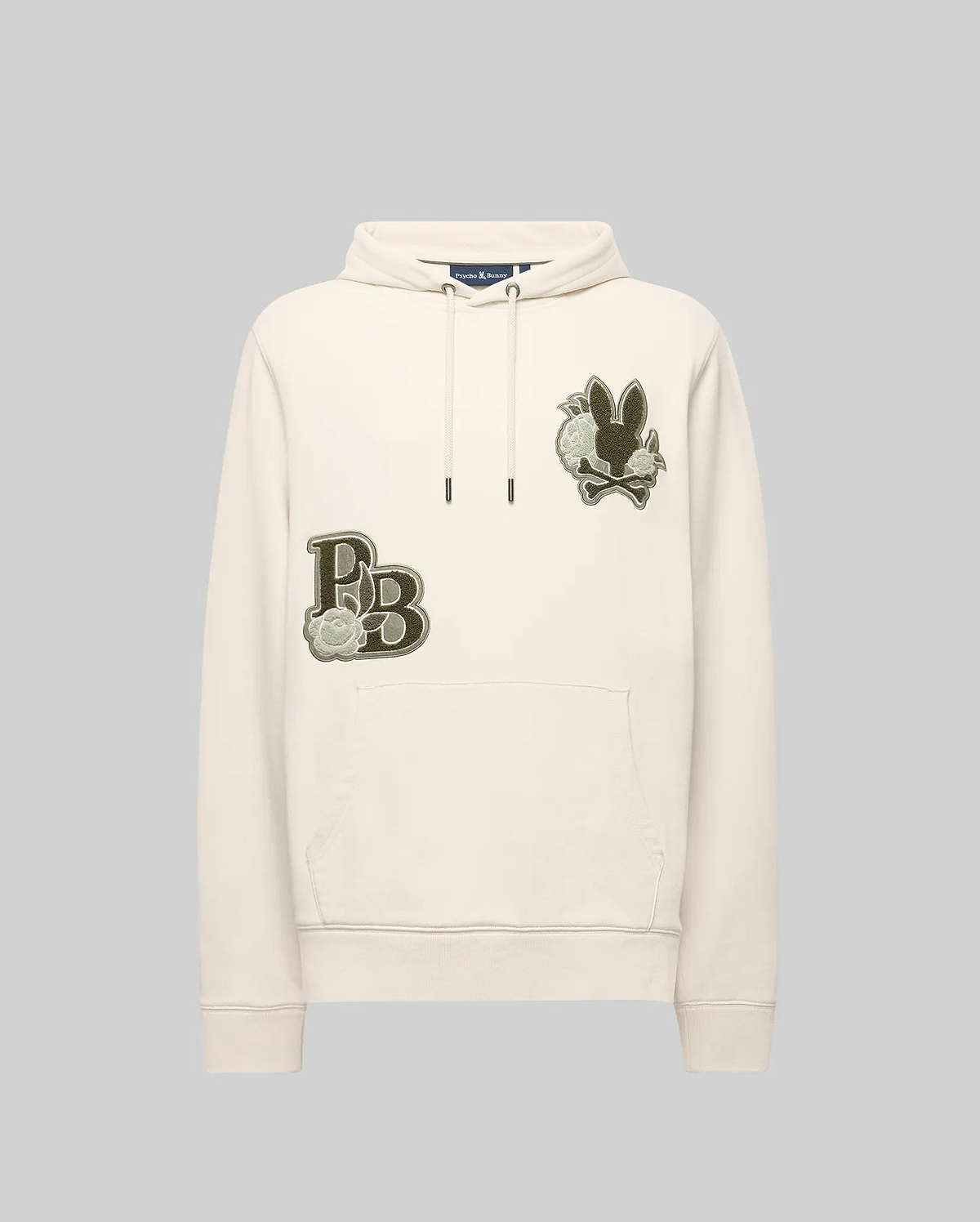 The Psycho Bunny MENS AUGUSTE HOODIE (MT0500043) is a cream regular-fit cotton hoodie with a front pocket, olive green chest patches, stylized lettering, and a chenille floral-detailed bunny graphic.