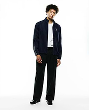 Mens Harland Double Weave Chalk Stripe Track Jacket in navy with white vertical pinstripes, a full zip, stand collar, and a small embroidered Psycho Bunny skull logo on the left chest, featuring white accent stripes on the sleeves. (5)