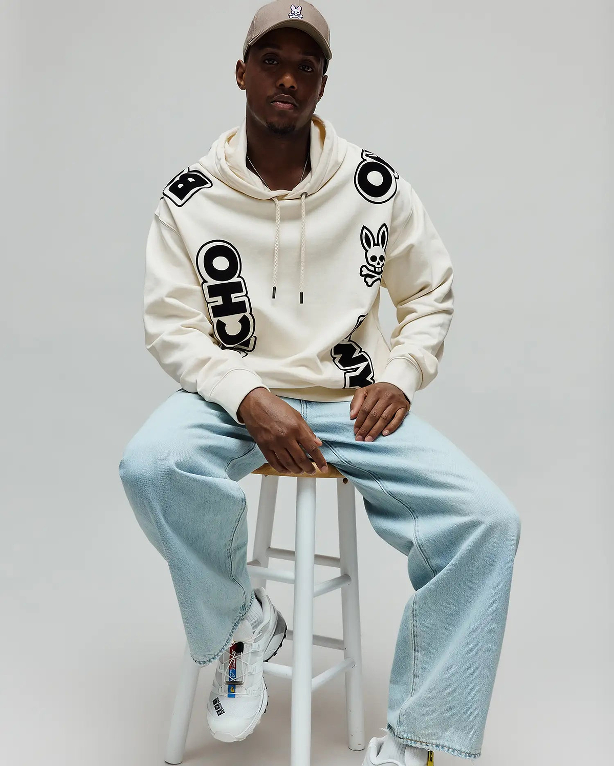 Mens Toby Oversized Hoodie in cream, featuring scattered large black Psycho Bunny skull logos and bold PSYCHO BUNNY lettering, with a relaxed fit and soft fleece texture. (3)