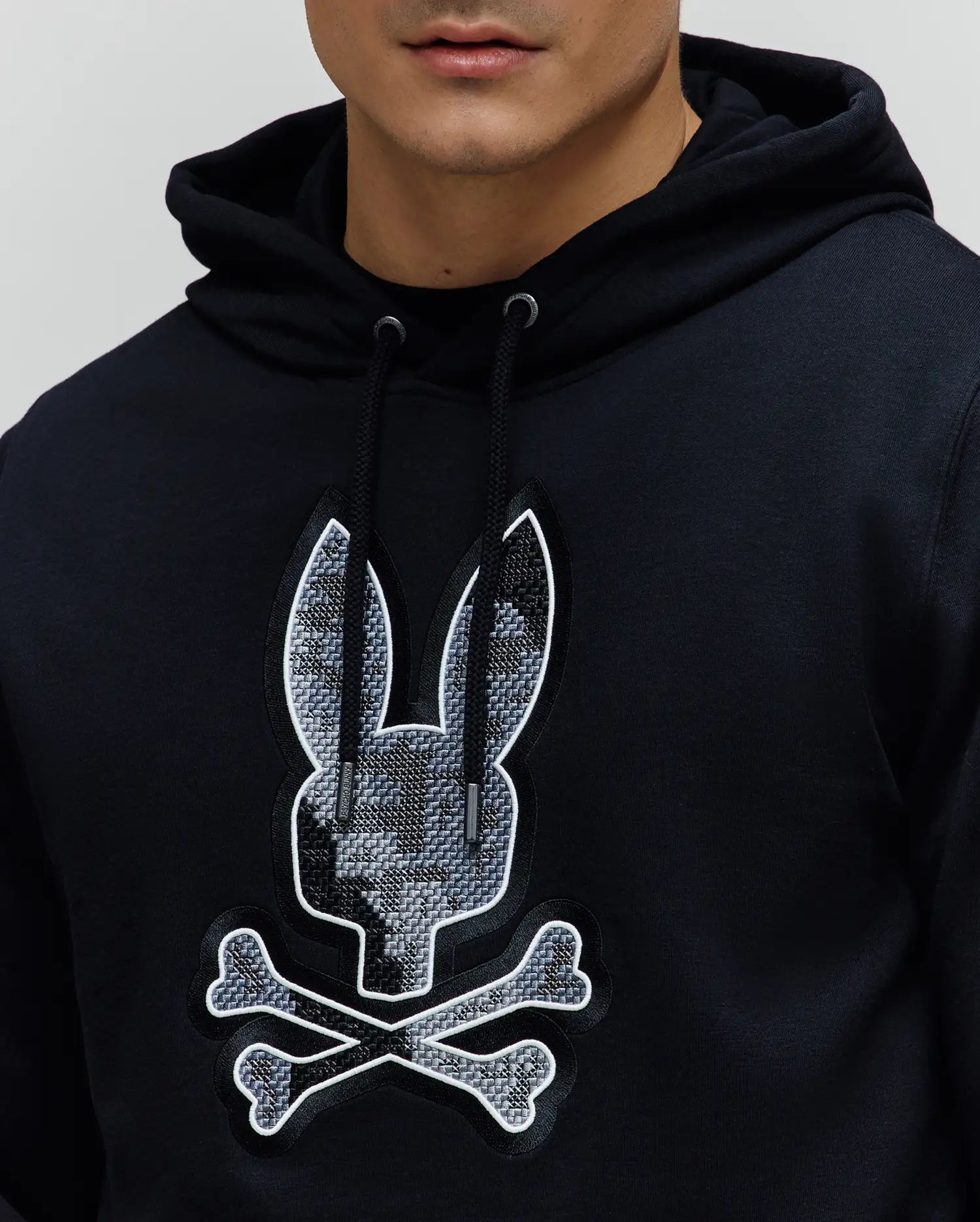 Black Mens Olivier Embroidered Hoodie, classic fit French terry, with a drawstring hood and large central chest embroidered Psycho Bunny skull logo featuring a grey geometric pattern and white outline.