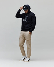 Mens Olivier Embroidered Hoodie: Relaxed fit navy French terry hoodie featuring a large white embroidered Psycho Bunny skull logo on the chest, complemented by beige cargo pants and a black logo cap.