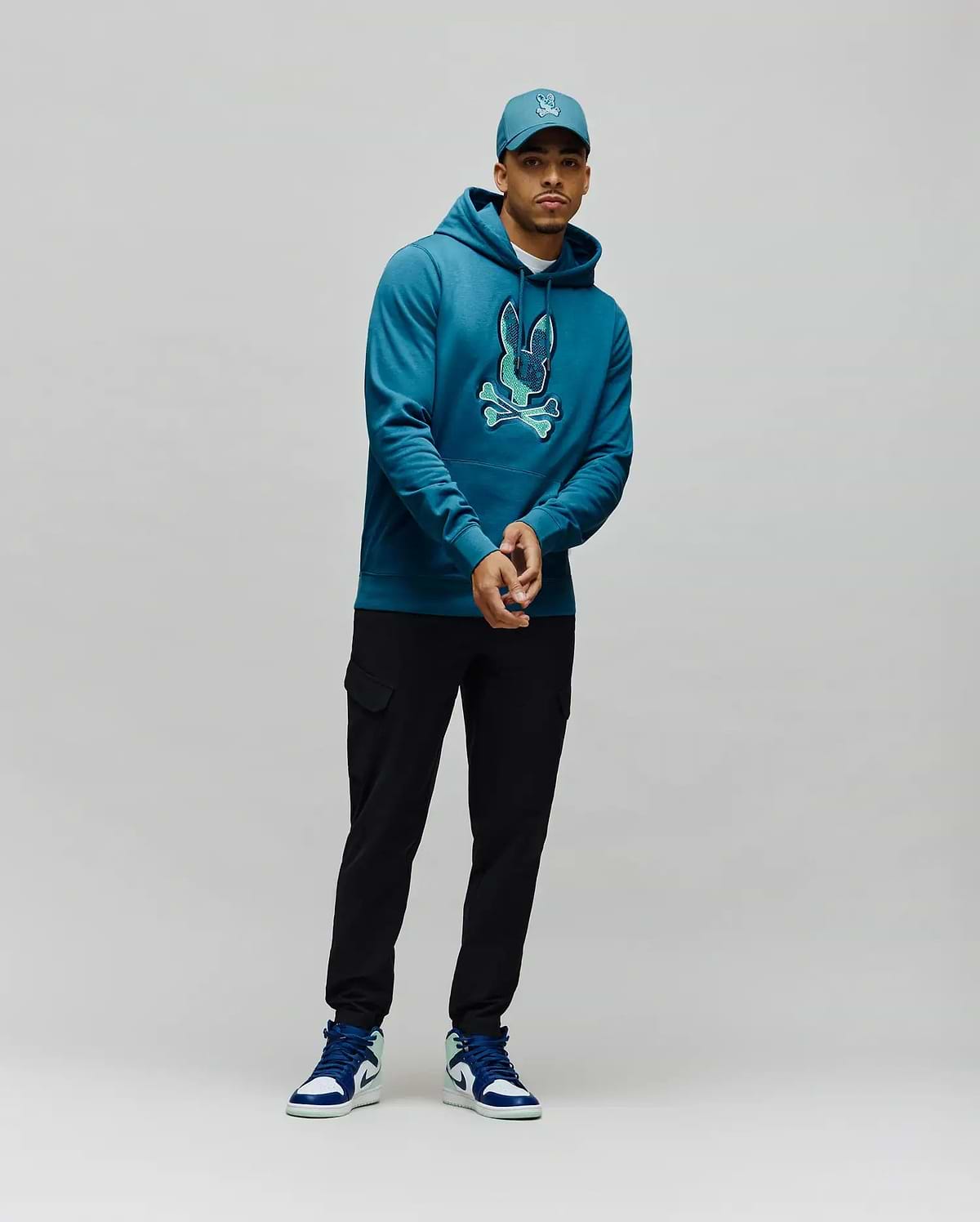Mens Olivier Embroidered Hoodie, a classic fit deep teal french terry hoodie with a large, vibrant light teal embroidered Psycho Bunny skull logo on the center chest. (4)