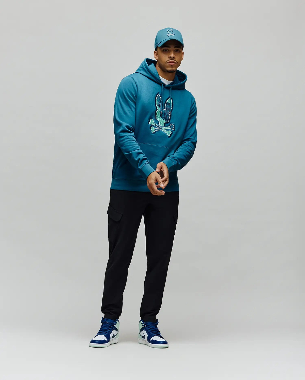 Mens Olivier Embroidered Hoodie, a classic fit deep teal french terry hoodie with a large, vibrant light teal embroidered Psycho Bunny skull logo on the center chest. (4)