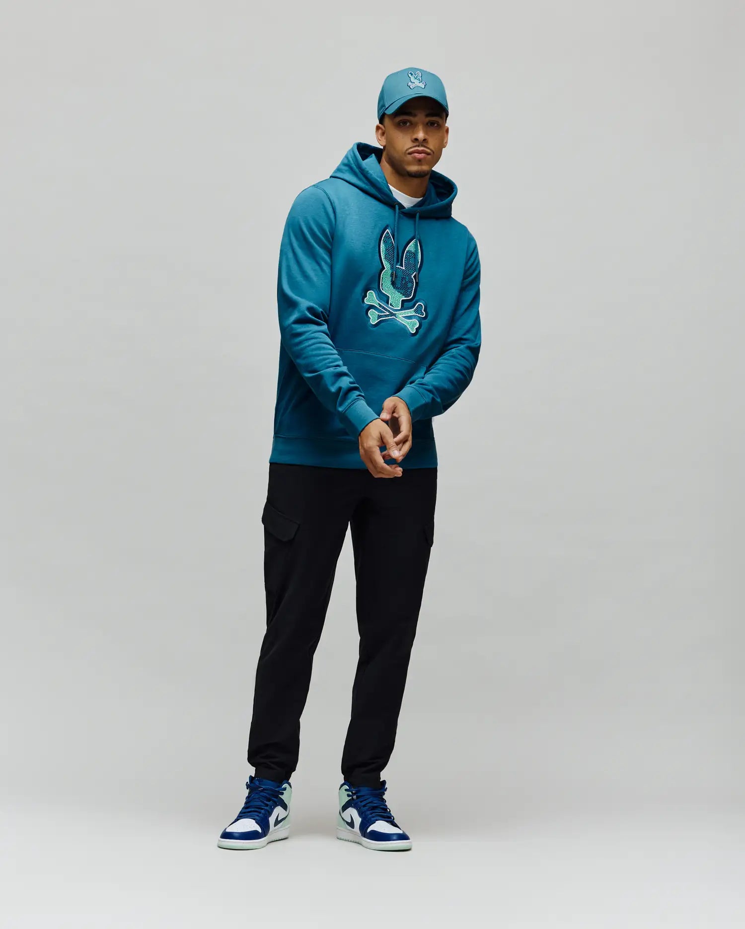 Mens Olivier Embroidered Hoodie, a classic fit deep teal french terry hoodie with a large, vibrant light teal embroidered Psycho Bunny skull logo on the center chest. (4)