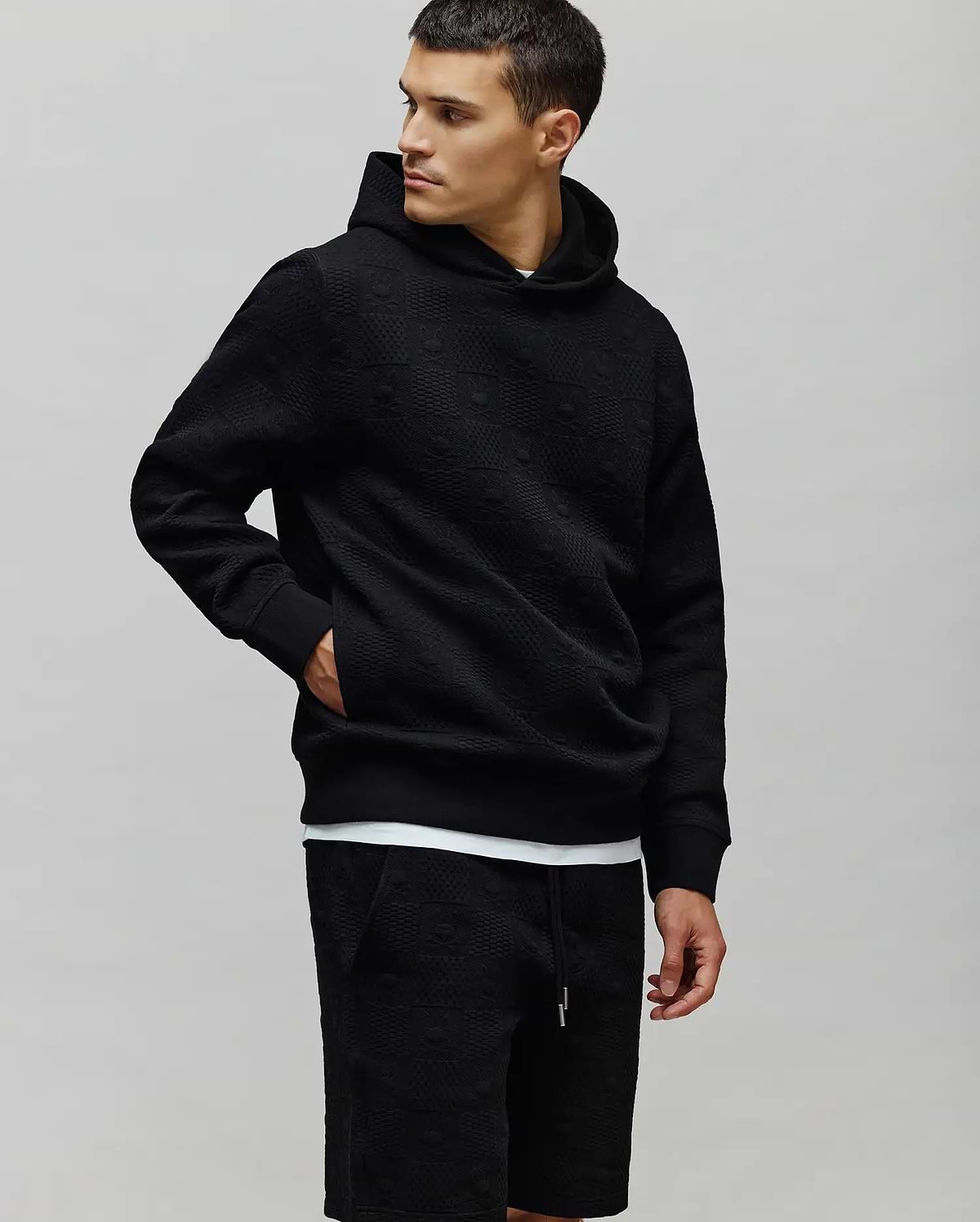 Black Mens Dustin Hoodie featuring a relaxed fit, textured jacquard fabric with an all-over embossed Psycho Bunny skull logo pattern, complete with ribbed cuffs and hem. (3)