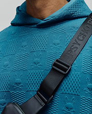 MENS DUSTIN HOODIE in vibrant teal, featuring a textured jacquard knit fabric with an all-over embossed Psycho Bunny skull and crossbones pattern, classic fit.