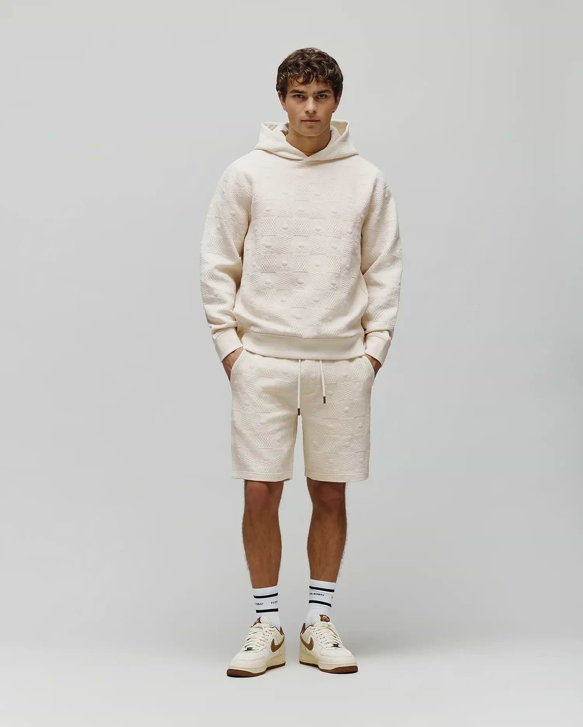 Cream Mens Dustin Hoodie and matching shorts, both featuring a relaxed fit and an allover embossed Psycho Bunny skull pattern on textured French terry fabric.