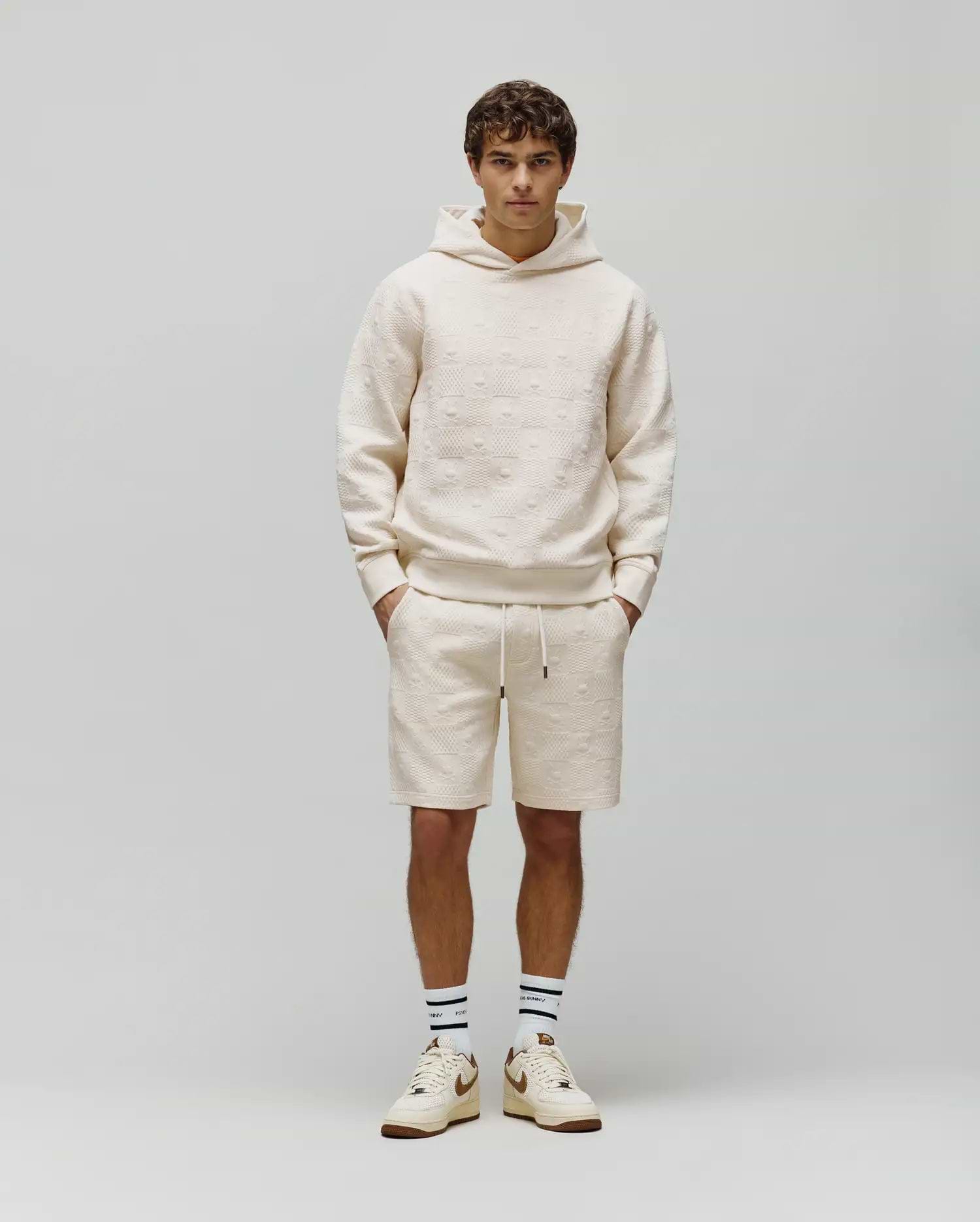 Cream Mens Dustin Hoodie and matching shorts, both featuring a relaxed fit and an allover embossed Psycho Bunny skull pattern on textured French terry fabric.