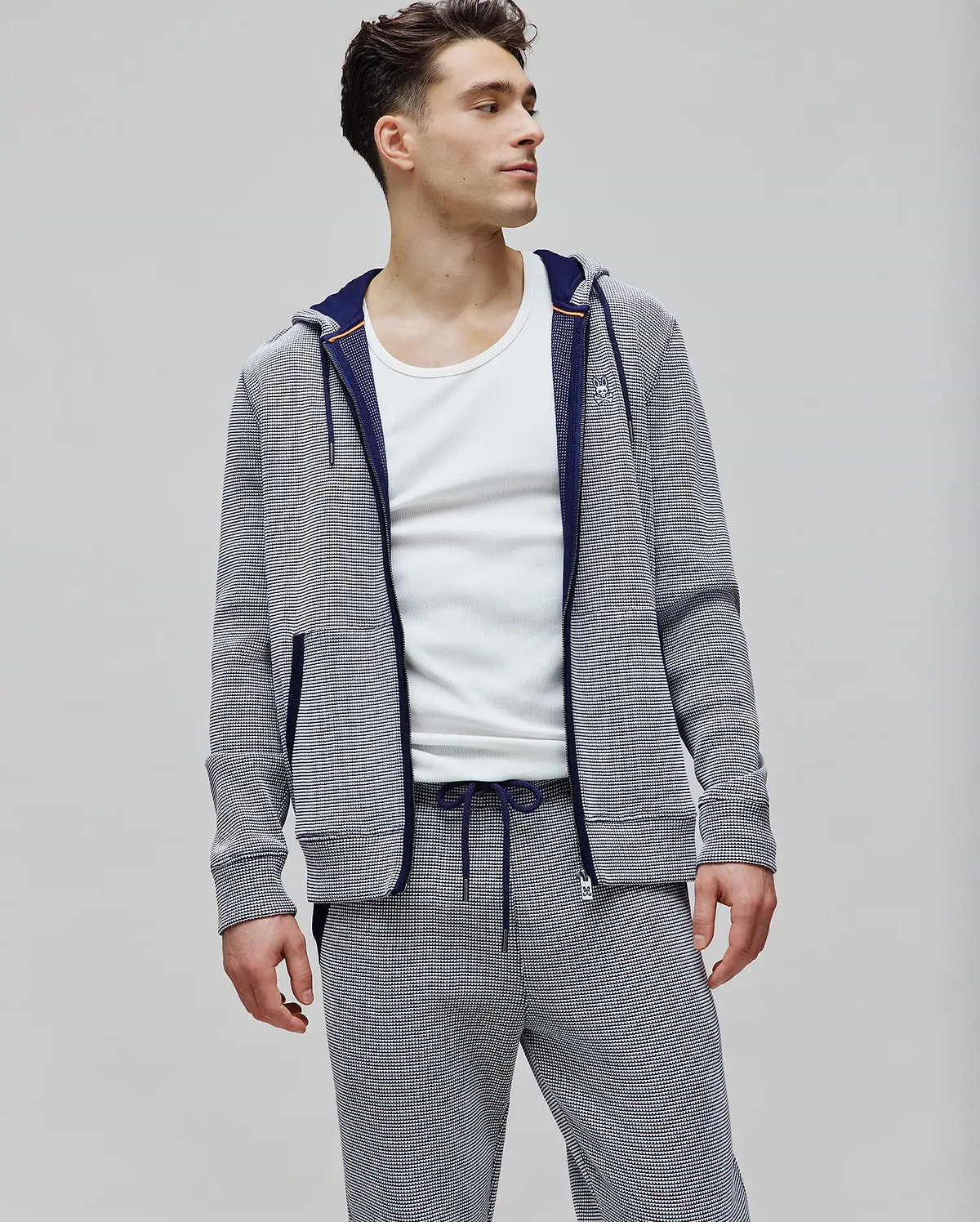 Mens Maxton Waffle Full Zip Hoodie in navy and white micro-stripe waffle knit, featuring a classic fit, small embroidered Psycho Bunny skull logo on the left chest, navy zipper, and orange hood trim.