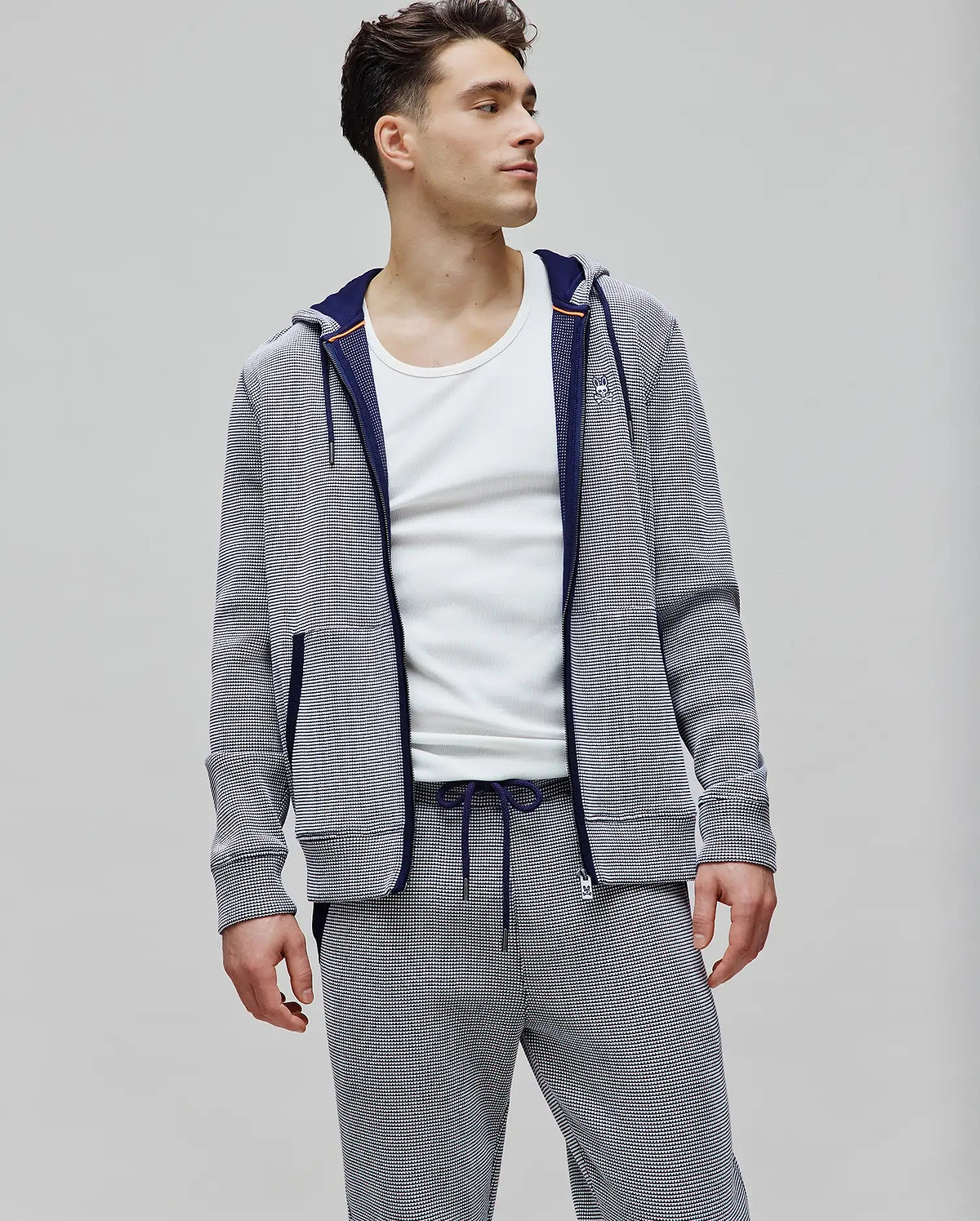 Mens Maxton Waffle Full Zip Hoodie in navy and white micro-stripe waffle knit, featuring a classic fit, small embroidered Psycho Bunny skull logo on the left chest, navy zipper, and orange hood trim.