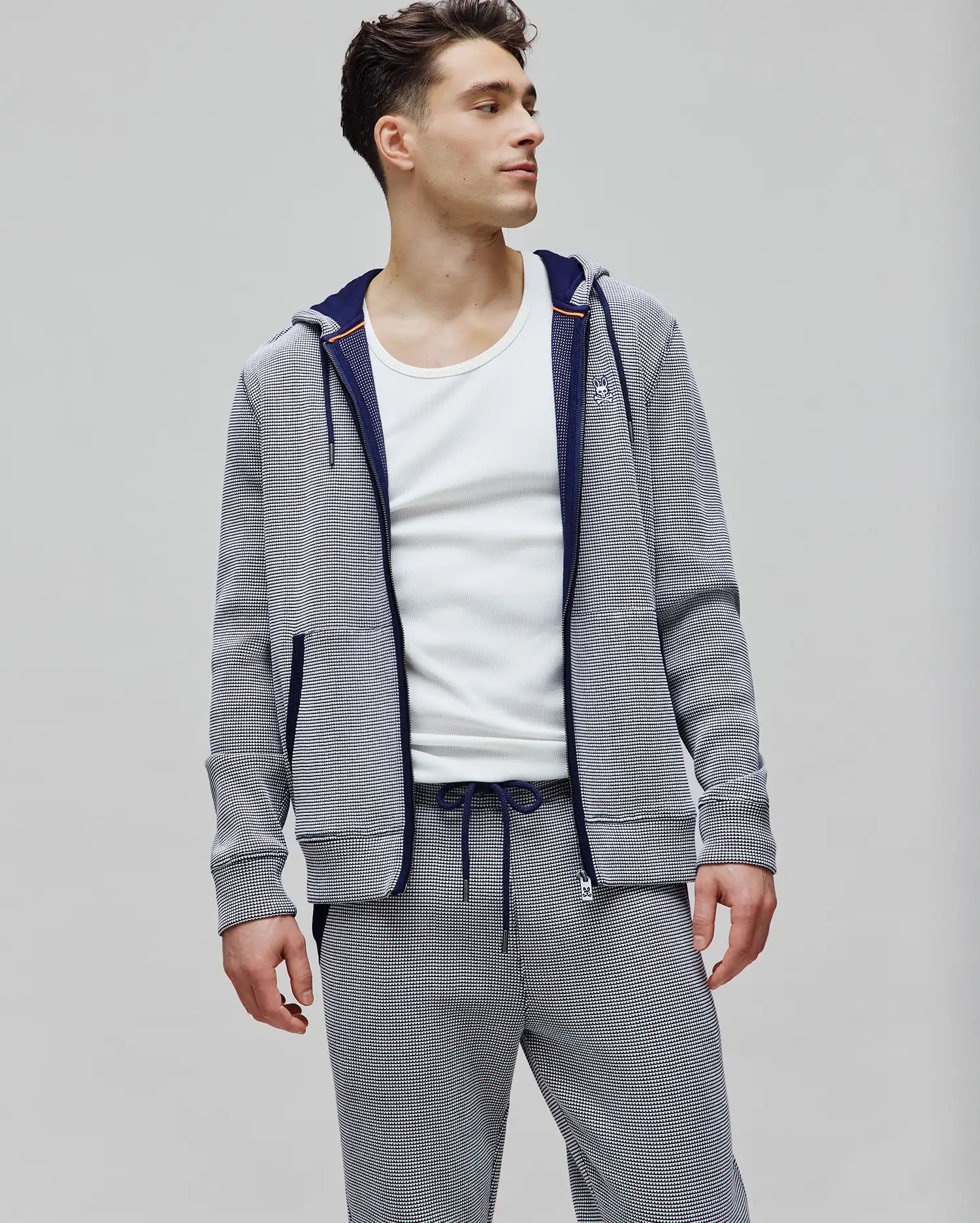 Mens Maxton Waffle Full Zip Hoodie in navy and white micro-stripe waffle knit, featuring a classic fit, small embroidered Psycho Bunny skull logo on the left chest, navy zipper, and orange hood trim.