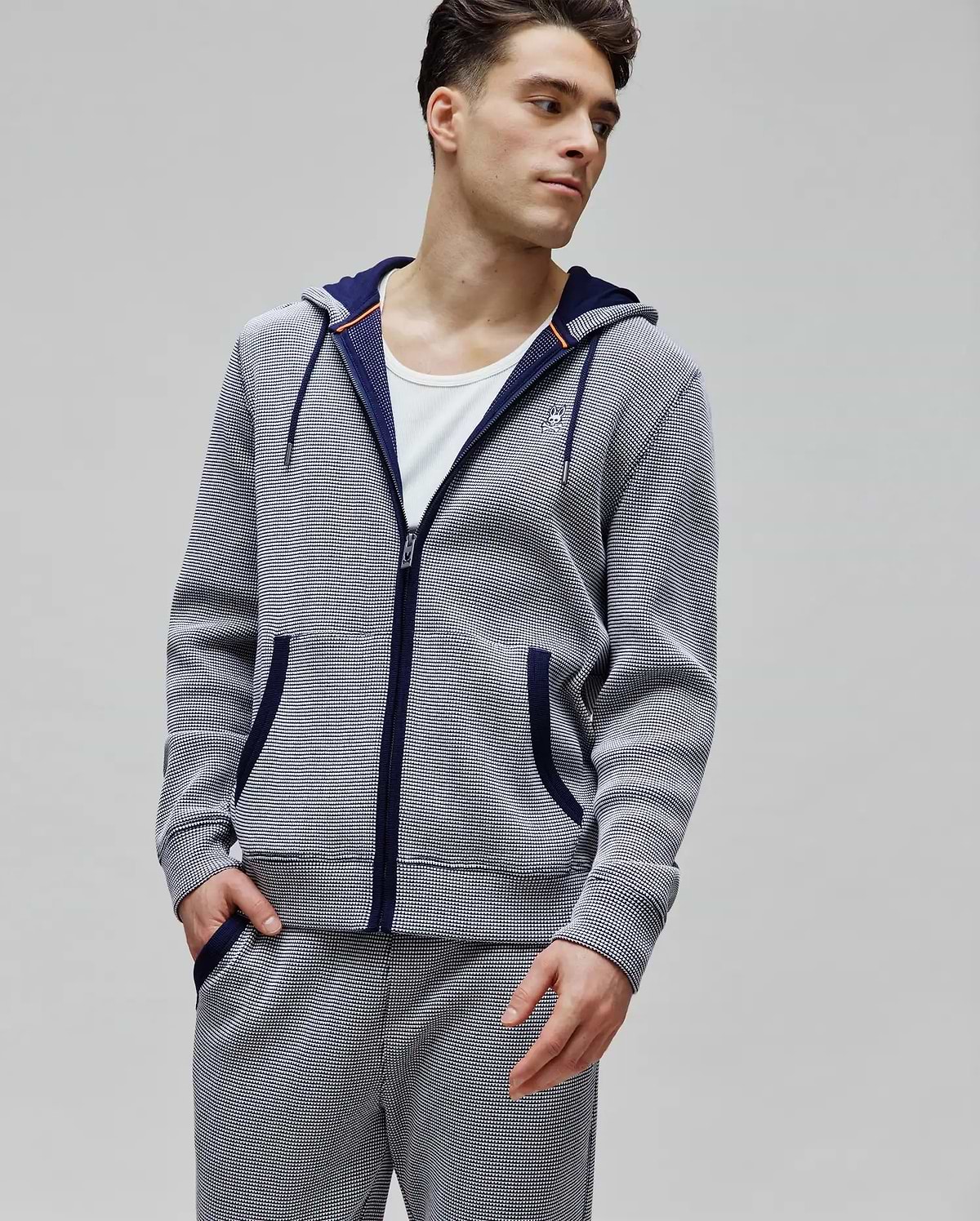 Mens Maxton Waffle Full Zip Hoodie in navy and white waffle knit, featuring a classic fit, full zip, drawstring hood with orange accents, front pockets, and a small embroidered Psycho Bunny skull logo on the left chest.