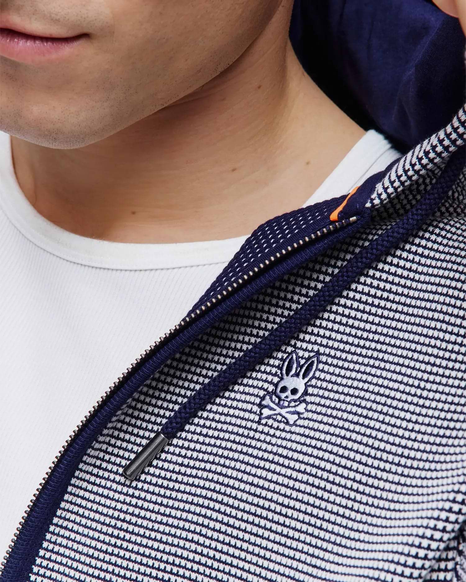 Mens Maxton Waffle Full Zip Hoodie in navy and white waffle knit, featuring a full zip closure with an orange accent, navy drawstrings, and a small embroidered Psycho Bunny skull logo on the chest.