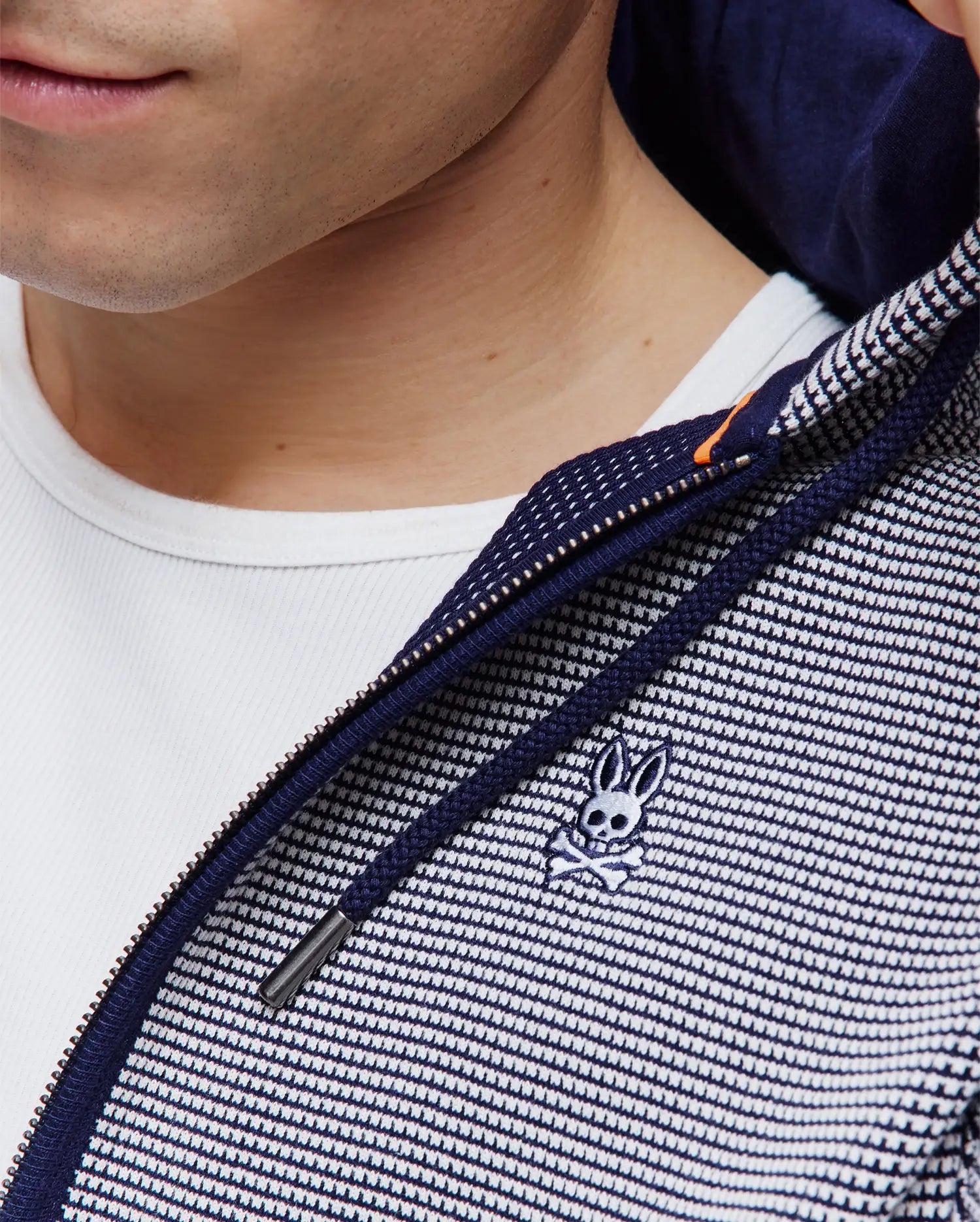 Mens Maxton Waffle Full Zip Hoodie in navy and white waffle knit, featuring a full zip closure with an orange accent, navy drawstrings, and a small embroidered Psycho Bunny skull logo on the chest.