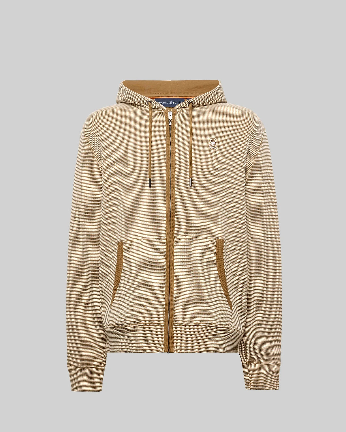 Mens Maxton Waffle Full Zip Hoodie in tan with a fine grid pattern, featuring brown zipper, drawstrings, and pocket trim. A small embroidered Psycho Bunny skull logo adorns the left chest.