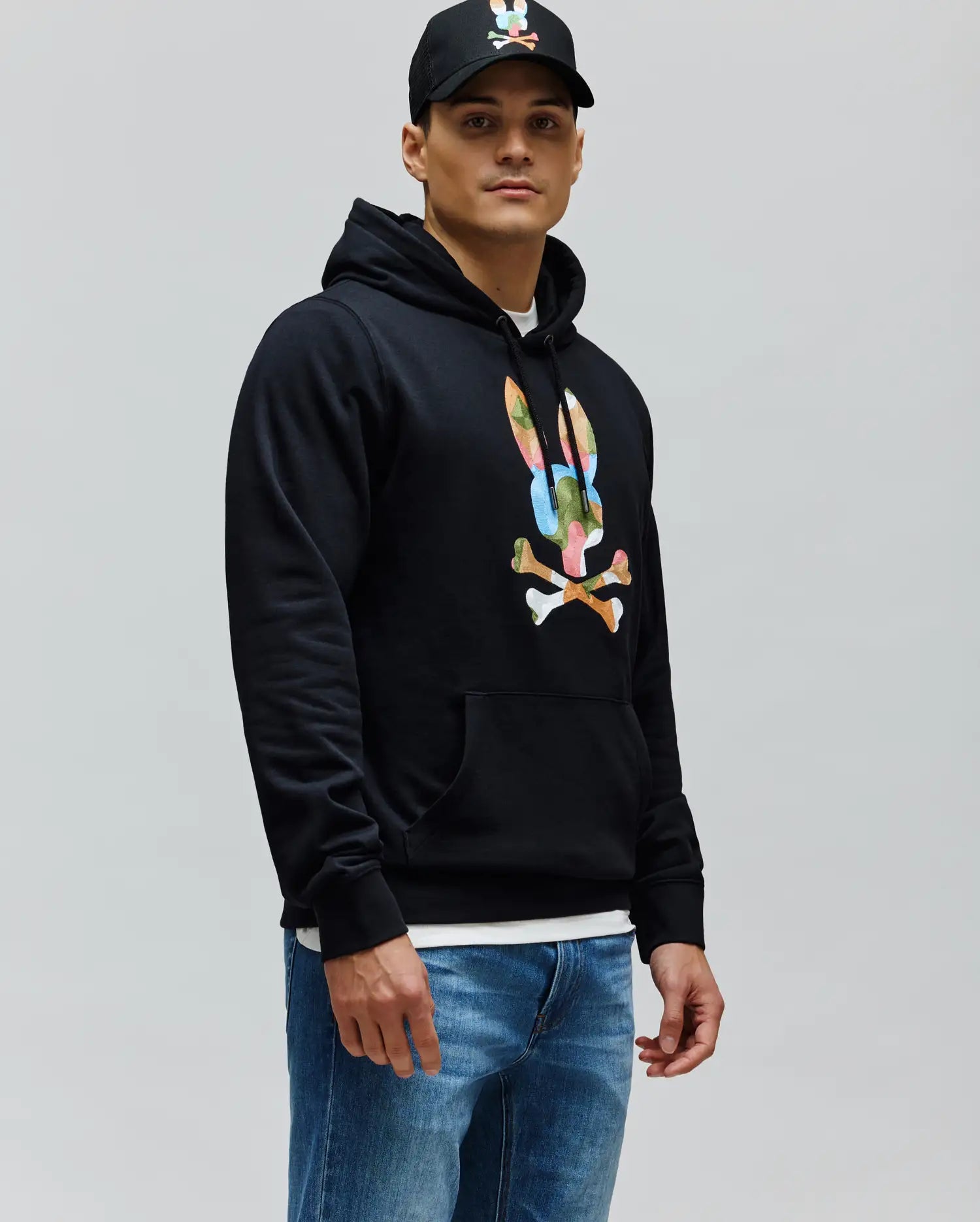 Mens Ara Hoodie in black, classic fit, soft cotton blend fleece, featuring a large, vibrant multi-color camouflage Psycho Bunny skull logo on the chest, with a drawstring hood and kangaroo pocket.