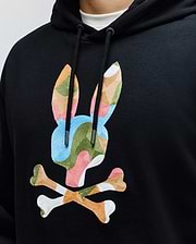 Mens Ara Hoodie: Black french terry hoodie with a large, central embroidered Psycho Bunny skull logo in a vibrant multi-color camouflage pattern, featuring branded drawstring tips and a relaxed fit.