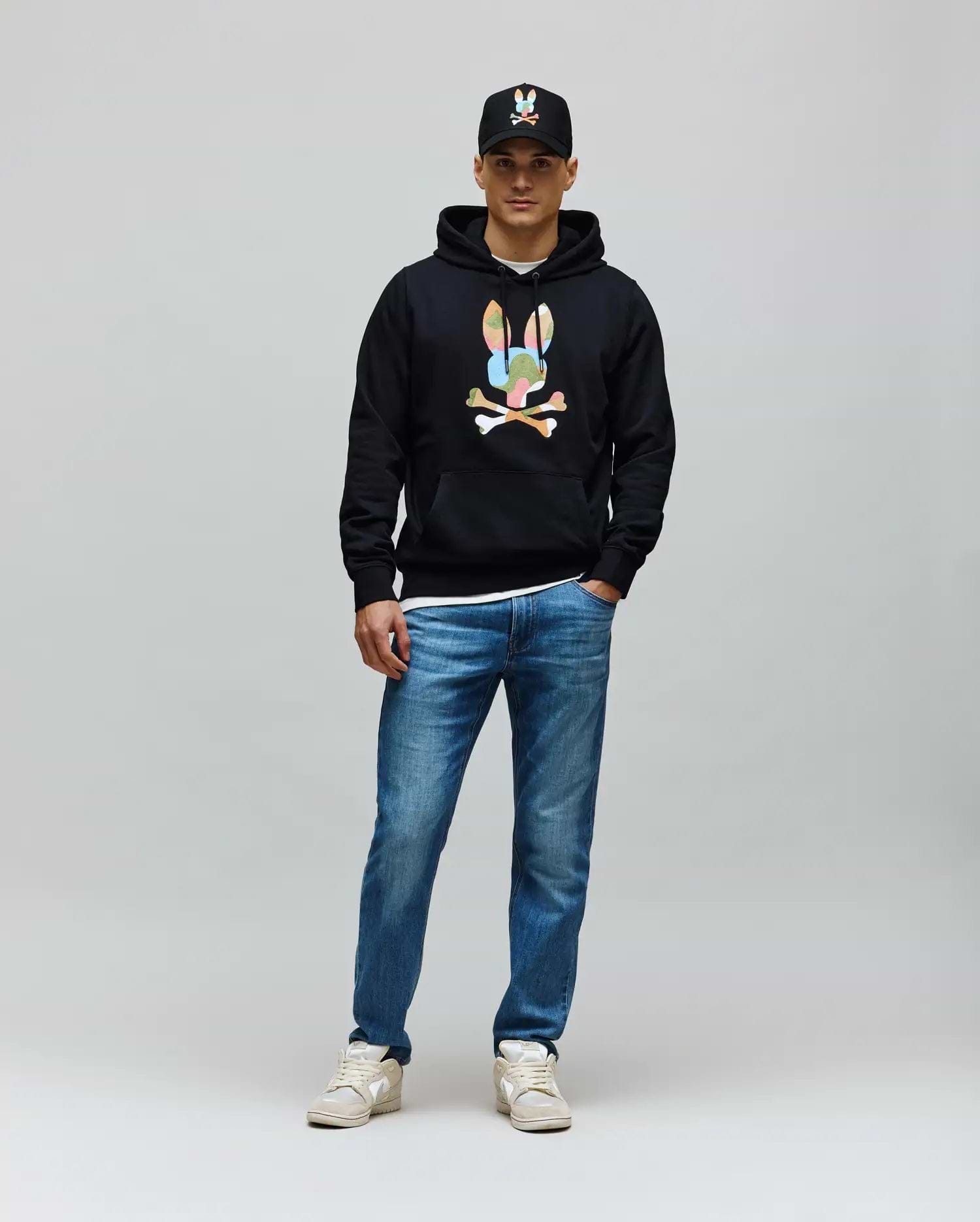 Mens Ara Hoodie, black classic fit with soft French terry fabric, featuring a large colorful Psycho Bunny skull and crossbones graphic on the center chest and a front kangaroo pocket.