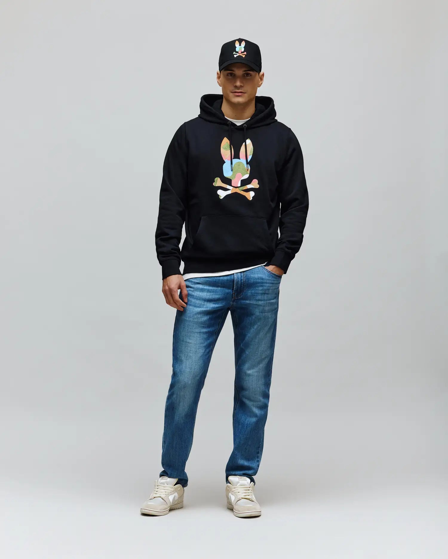 Mens Ara Hoodie, black classic fit with soft French terry fabric, featuring a large colorful Psycho Bunny skull and crossbones graphic on the center chest and a front kangaroo pocket.