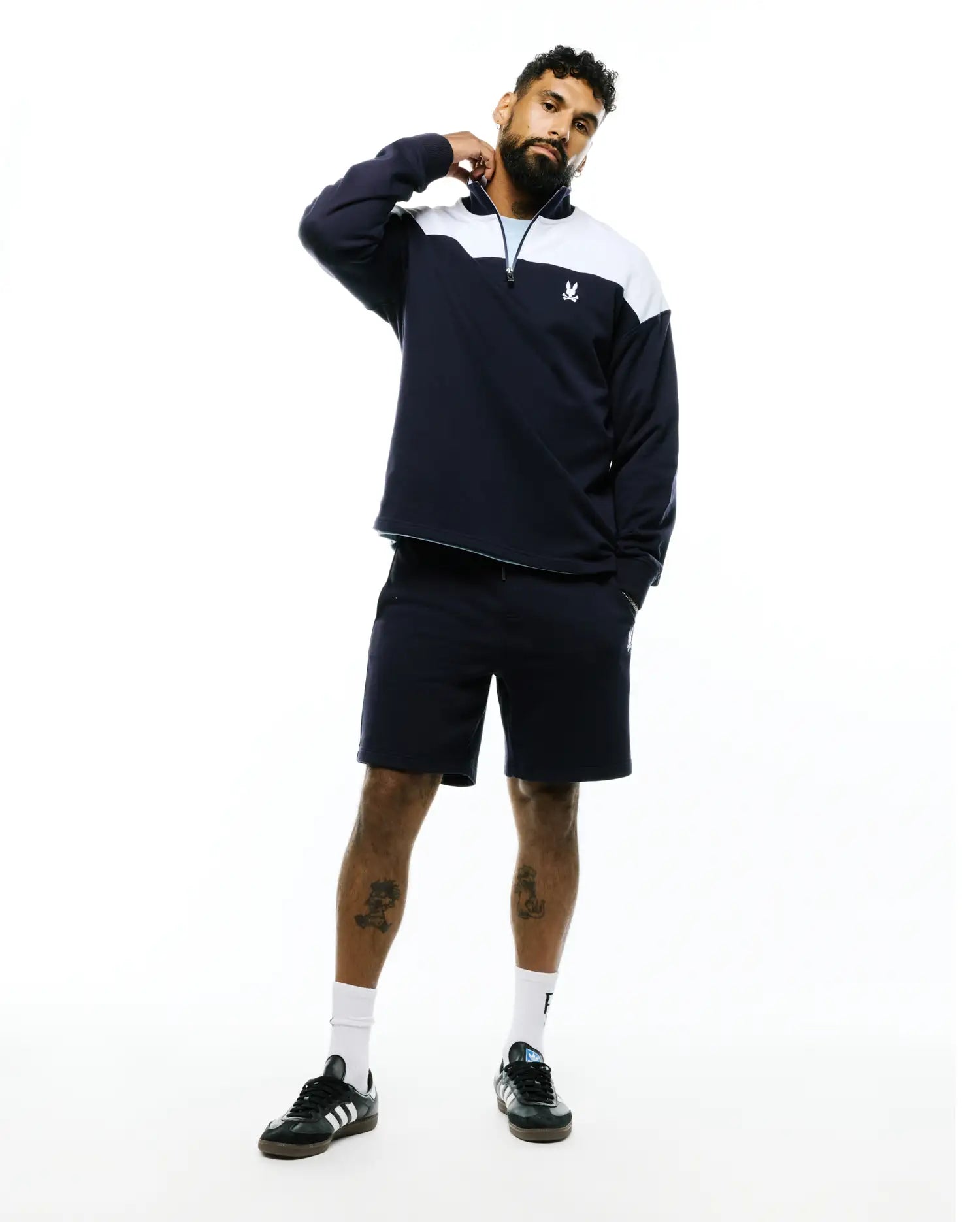 Mens Gabe French Terry 1/4 Zip in navy with white color block shoulders, light blue zipper trim, a relaxed fit, and a small embroidered Psycho Bunny skull logo on the left chest.
