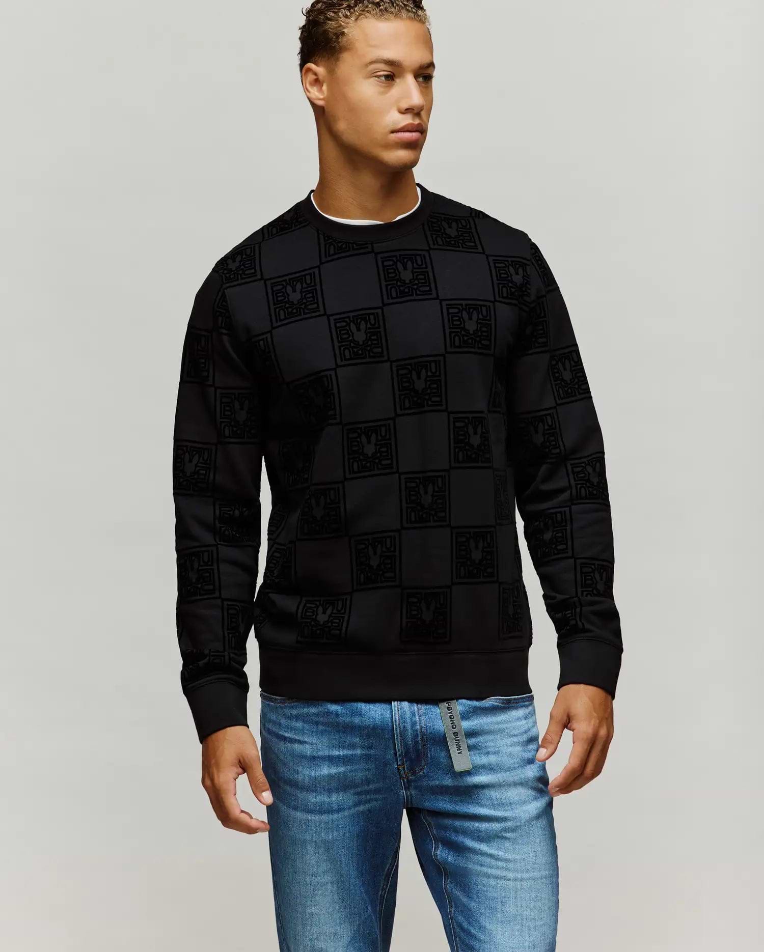Mens Gio All Over Flock Crew, a black classic fit sweatshirt featuring an all-over flocked checkerboard pattern with the iconic Psycho Bunny skull logo.