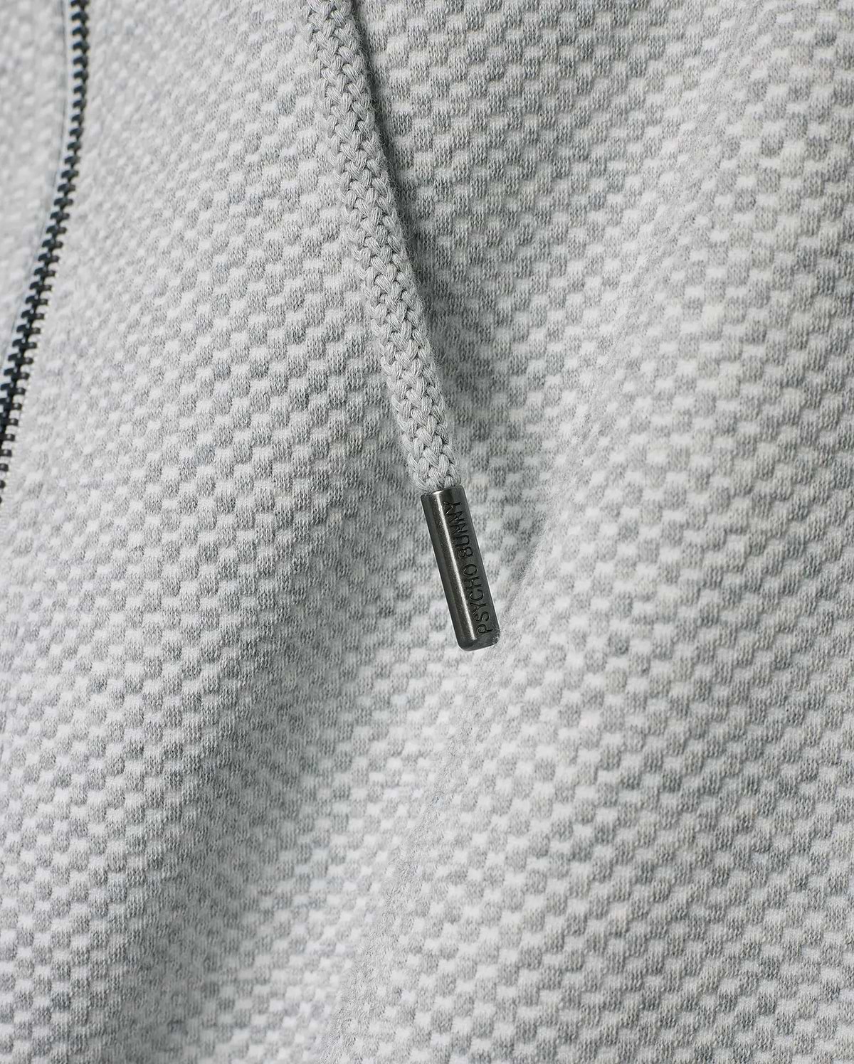 Mens Marc Textured Full Zip Hoodie in light grey with a distinct checkered knit pattern, featuring a dark zipper and a drawstring with an engraved Psycho Bunny metallic tip.
